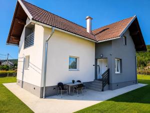 a small white house with a table and chairs at UP & DOWN Holiday House in Donji Prozor