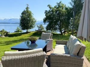 a patio with a table and chairs with a view of the water at Draget gård, idyllisk småbruk ved sjøen in Molde