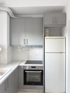 a kitchen with white cabinets and a refrigerator at Modern Sea View Apartment - Arkitsa Rentals in Arkitsa