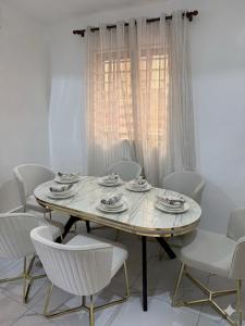 a white dining room with a table and chairs at Asibbey Lodge in Ashalebotwe +2 photos