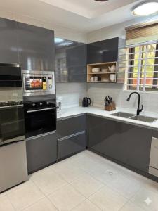 a kitchen with black cabinets and a sink and a microwave at Asibbey Lodge in Ashalebotwe