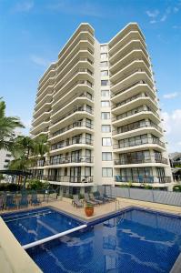 a large white apartment building with a swimming pool at Seaview Resort in Mooloolaba