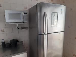 a stainless steel refrigerator in a kitchen with a microwave at Casa Vilarejo in Arembepe