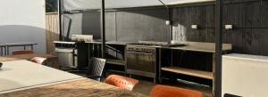 a kitchen with a stove and a table and chairs at Welcome Bay Hot Pools in Tauranga