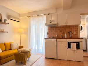 a living room with a yellow couch and a kitchen at Studio 28 in Chios +2 photos