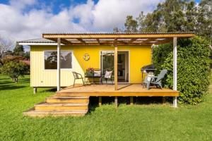 a small yellow house with a deck in the grass at Relax a Lodge in Kerikeri