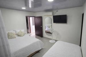 a white room with two beds and a mirror at Cerete Apartment 111 in Cereté +7 photos
