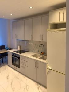 a kitchen with white cabinets and a stainless steel refrigerator at Modern Comfort Apartment - Arkitsa Rentals in Arkitsa
