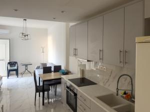 a kitchen with white cabinets and a table and a dining room at Modern Comfort Apartment - Arkitsa Rentals in Arkitsa +9 photos