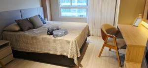 a bedroom with a bed with a chair and a desk at Apê Brisa-5min consulado EUA-garagem in Porto Alegre +12 photos