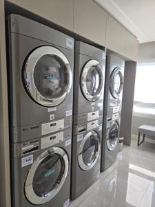 a row of four washing machines in a room at Apê Brisa-5min consulado EUA-garagem in Porto Alegre