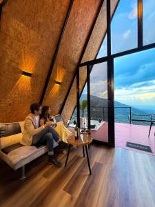 two people sitting on a couch in a room with a large window at Cabaña Nivura in Palmira