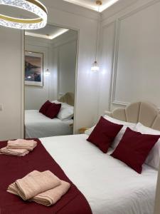 a bedroom with two beds with red pillows and a mirror at Gaglian's Suites Lake Como in Como
