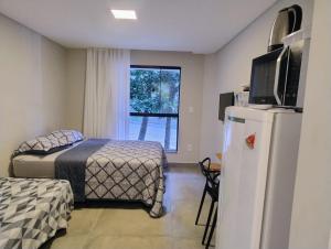 a bedroom with a bed and a refrigerator and a window at Villa Parati Bombinhas Sob Nova Direção in Bombinhas
