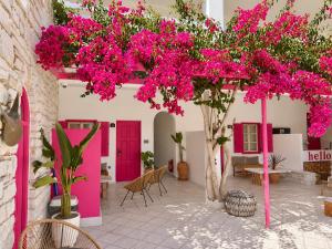 a courtyard with pink doors and a tree with pink flowers at Anchorage Paros Boutique & Private Beach in Piso Livadi