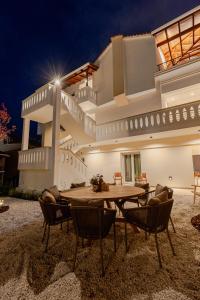 a table and chairs in front of a house at night at Anema Living in Parga