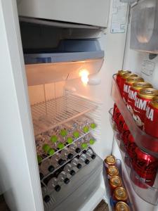 an open refrigerator filled with bottles and cans of soda at Pousada Paraiso in Telêmaco Borba