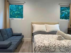 a bedroom with a bed and a couch and two windows at 1 full bed with En-Suite bath surrounded by greenery in Austin
