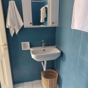 a blue bathroom with a sink and a basket at Captain's View Guesthouse in Kouniádhoi