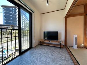 a living room with a tv and a large window at Sea Retreat Nika in Kawazu