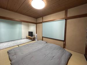 a bedroom with a bed and two large windows at Sea Retreat Nika in Kawazu