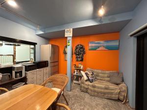 a living room with orange walls and a table at Sea Retreat Nika in Kawazu