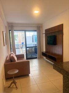 a living room with a couch and a flat screen tv at Condomínio Sol Marina in Camaçari