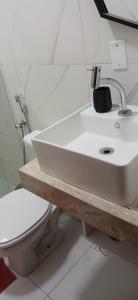 a bathroom with a white sink and a toilet at Condomínio Sol Marina in Camaçari