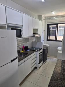 a white kitchen with a sink and a refrigerator at Condomínio Sol Marina in Camaçari