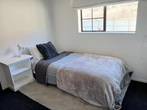 a white bedroom with a bed and a window at Cardrona mountain cottage in Cardrona