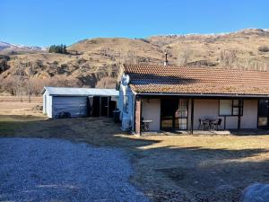 a house with a garage and a mountain in the background at Cardrona mountain cottage in Cardrona