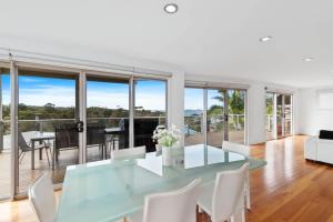 a dining room with a glass table and white chairs at Three Sisters at Long Beach in Long Beach
