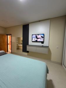 a bedroom with a bed and a tv on the wall at casa conforto e piscina in Sinop