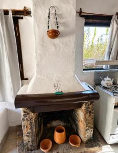 a kitchen with a stone fireplace with pots at Cabañas el cardon in Maimará +7 photos