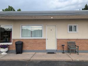 a brick house with a white door and a trash can at Lang's Motel in Wabigoon