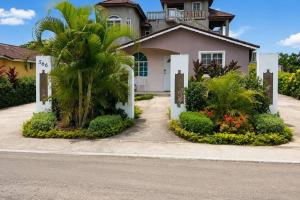 a house with a palm tree in front of it at The Hideaway Suite, largest master, ocean glimpse in Florence Hall