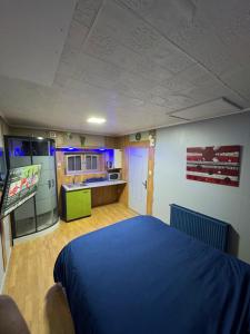a bedroom with a blue bed and a kitchen at Studio St Florentin 2 in Saint-Florentin