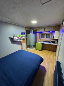 a bedroom with a blue bed and a kitchen at Studio St Florentin 2 in Saint-Florentin