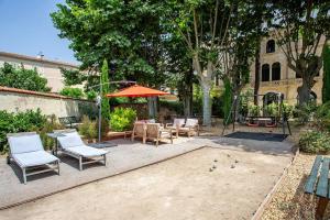 a patio with chairs and tables and an umbrella at 5 Family Apartments with Pool & Large Garden in Historic Pézenas Convent in Pézenas