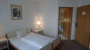 una camera da letto con un letto bianco con una lampada e una porta di Gästehaus Langhammer a Bubenreuth