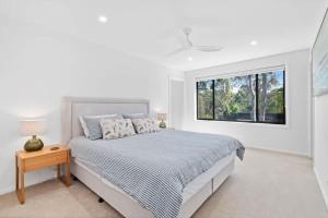 a white bedroom with a bed and a window at Tranquil at Rosedale in Tomakin +9 photos