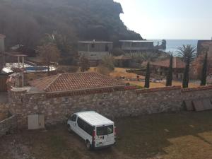 a white van parked in front of a stone wall at Buljarica Bay Apartments in Petrovac na Moru
