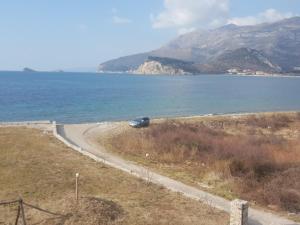 a car parked on a road next to the ocean at Buljarica Bay Apartments in Petrovac na Moru