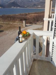 a bowl of fruit and a bottle of wine on a balcony at Buljarica Bay Apartments in Petrovac na Moru
