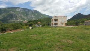 a house in a field with mountains in the background at Buljarica Bay Apartments in Petrovac na Moru
