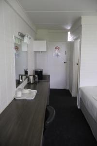 a kitchen with a counter and a bed in a room at Hilltop Hotel in Goonellabah