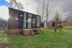 a tiny house sitting on top of a lush green field at Wahi Marie X by Tiny Away in Puketitiri