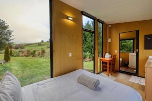 a bedroom with a bed and a large window at Wahi Marie X by Tiny Away in Puketitiri