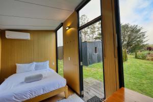 a bedroom with a bed and a sliding glass door at Wahi Marie X by Tiny Away in Puketitiri +16 photos