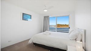 a white bedroom with a bed and a window at Quayside in Nambucca Heads